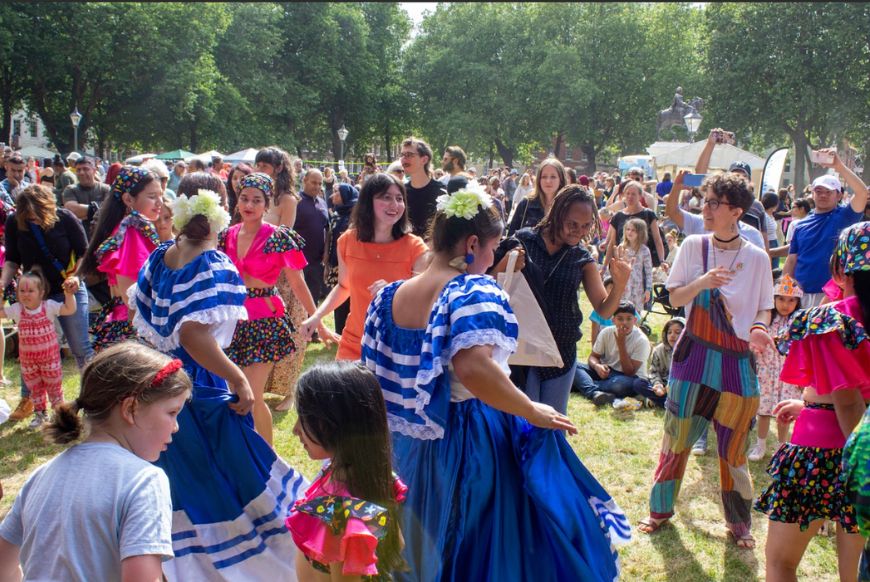 people dancing with and watching two women in latin american dresses dance